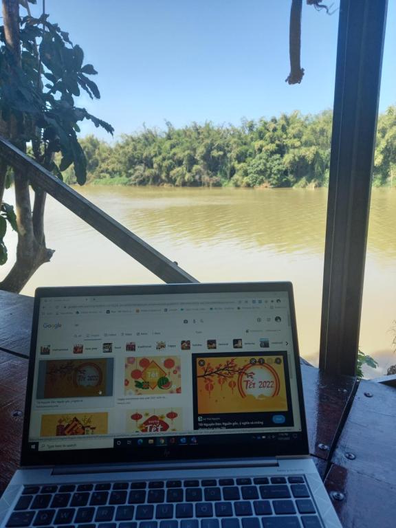 Tân PhúLittlefarm - Nam Cat Tien的坐在河前桌子上的笔记本电脑