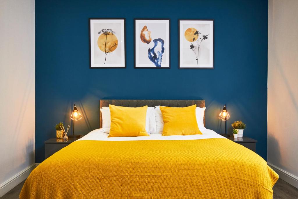 利兹Stunning 2 bed Apartment - Central Location的卧室配有一张黄色的床,墙上挂着四张照片