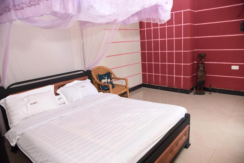 坎帕拉Trinity Resort Hotel & Spa的一间卧室配有一张床和一把椅子