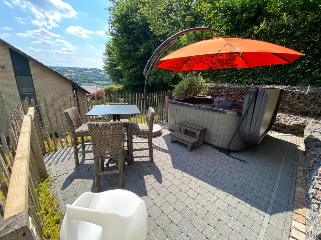 马尔梅迪Livremont7的一个带桌子和遮阳伞的庭院和一个热水浴缸
