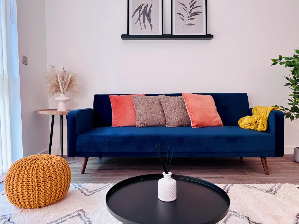 伦敦NEW Cosy 3BR Apartment With Private Garden In Olympic Park的客厅配有一张蓝色的沙发,配有一张桌子