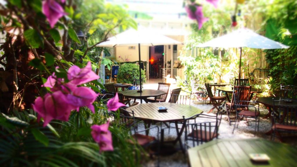 锡切斯Privat Hotel Liberty Sitges的一个带桌椅和紫色鲜花的庭院