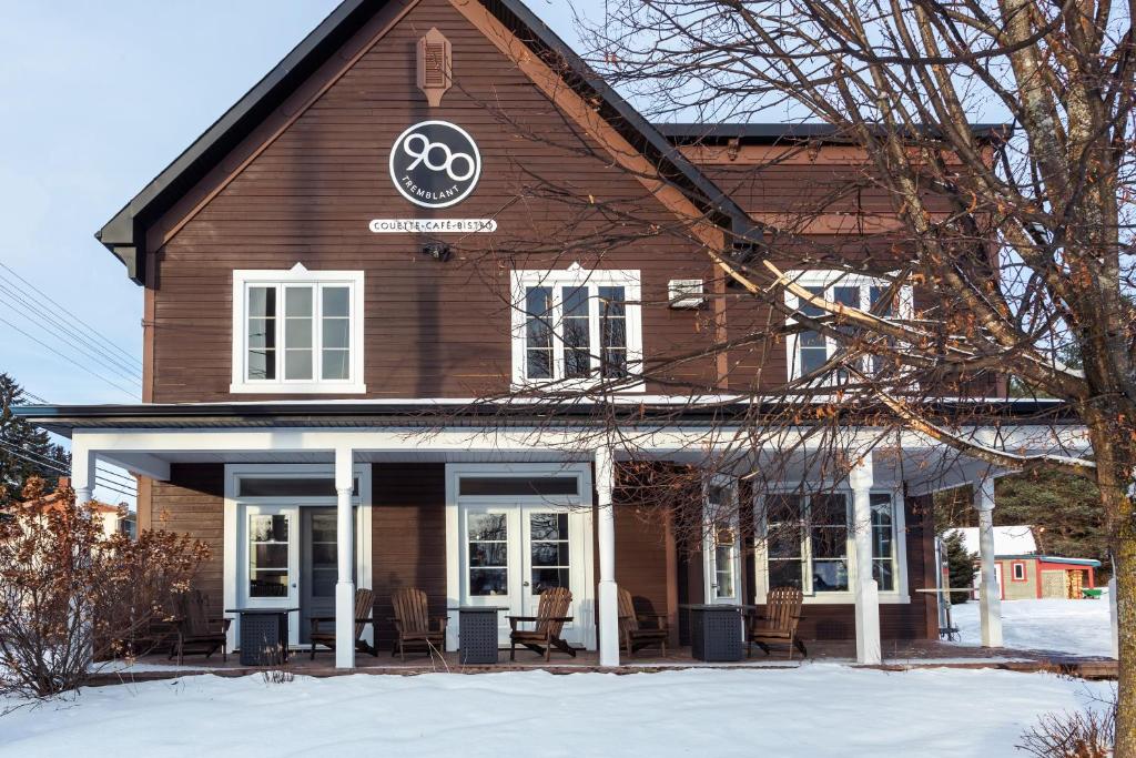 蒙特朗布朗Le 900 Tremblant Inn Café and Bistro的雪上标有标志的棕色建筑