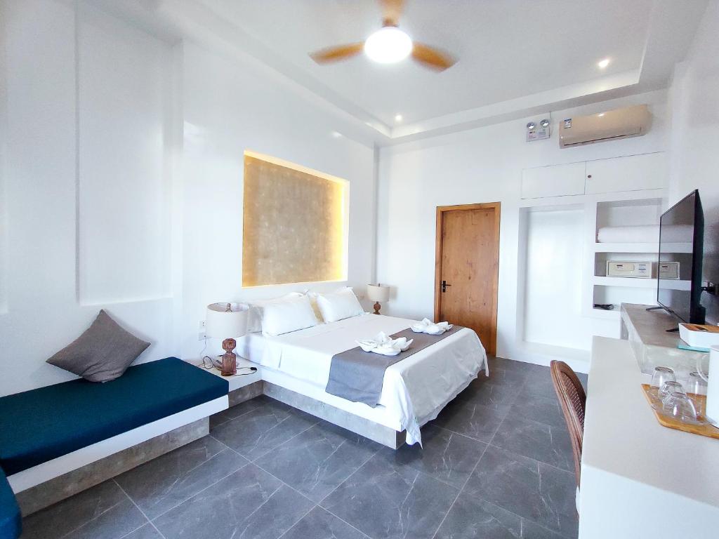 TaiwalaBohol Coastal View Hotel的一间卧室配有一张床、一张沙发和一台电视。