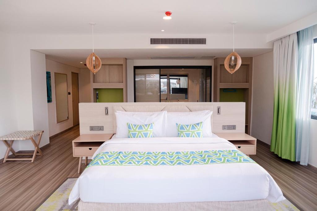 马尼拉Lime Resort Manila的卧室配有带绿色窗帘的大型白色床