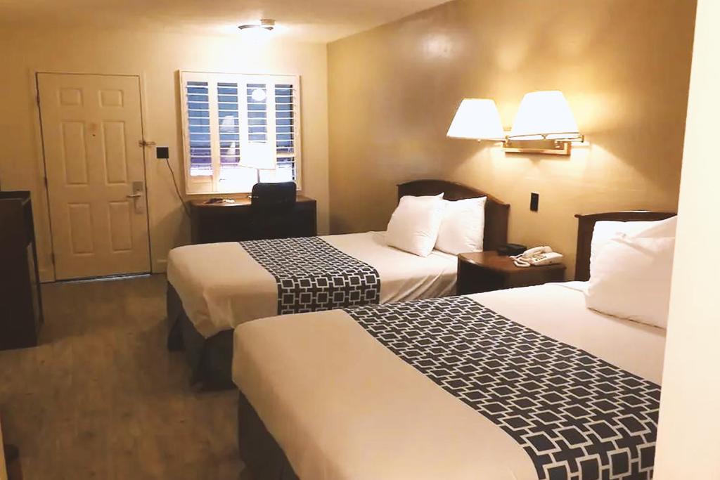 麦库克Coratel Inn & Suites by Jasper McCook的酒店客房设有两张床和窗户。
