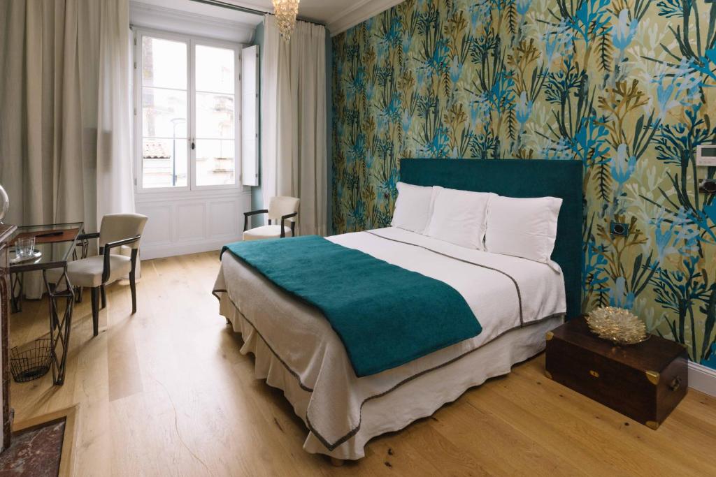 波尔多拉柯斯旅馆的一间卧室配有一张大床和一张桌子及椅子