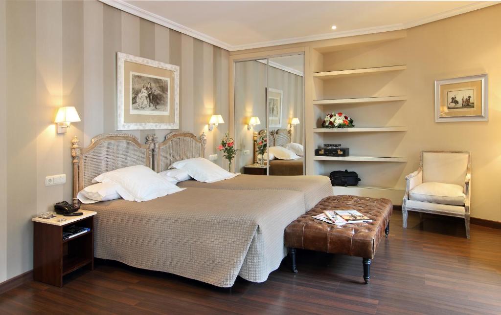 巴利亚多利德Hotel Imperial的一间卧室配有一张大床和一把椅子