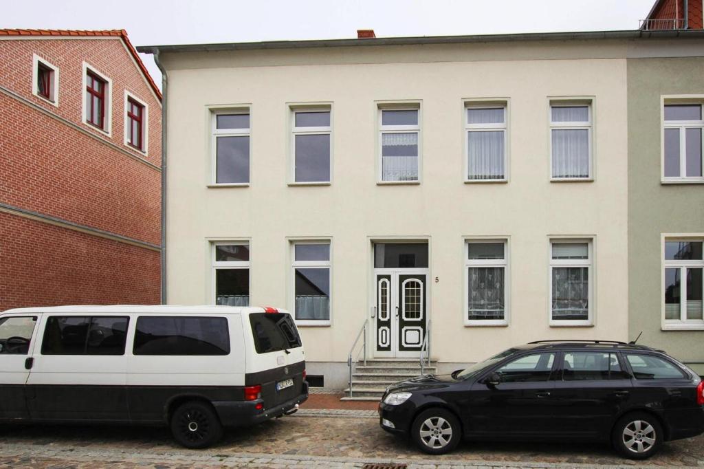 马尔肖Apartment in Malchow with terrace的停在大楼前的一辆白色面包车和一辆黑色汽车