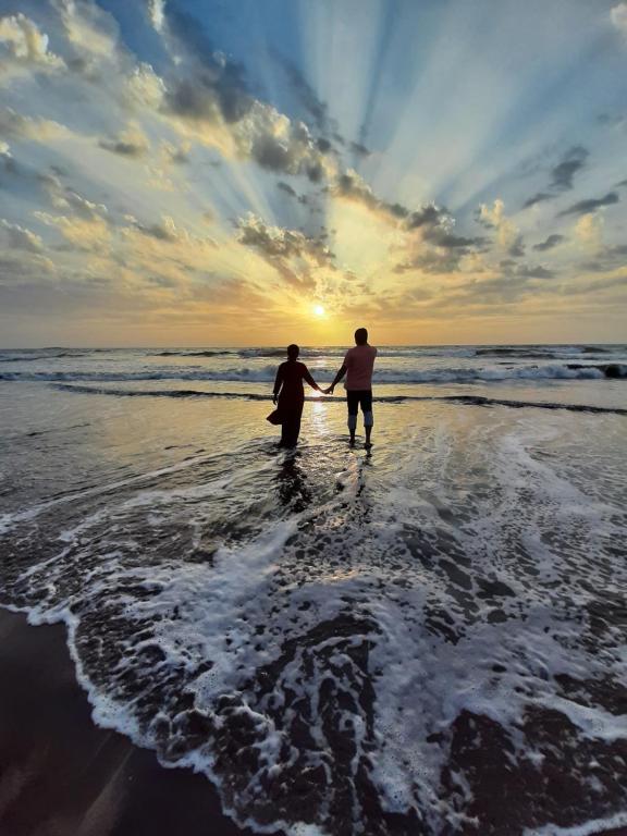 拉特纳吉里Windsongs A Premium Seaview Tropical Village的两个人在海滩上水中散步