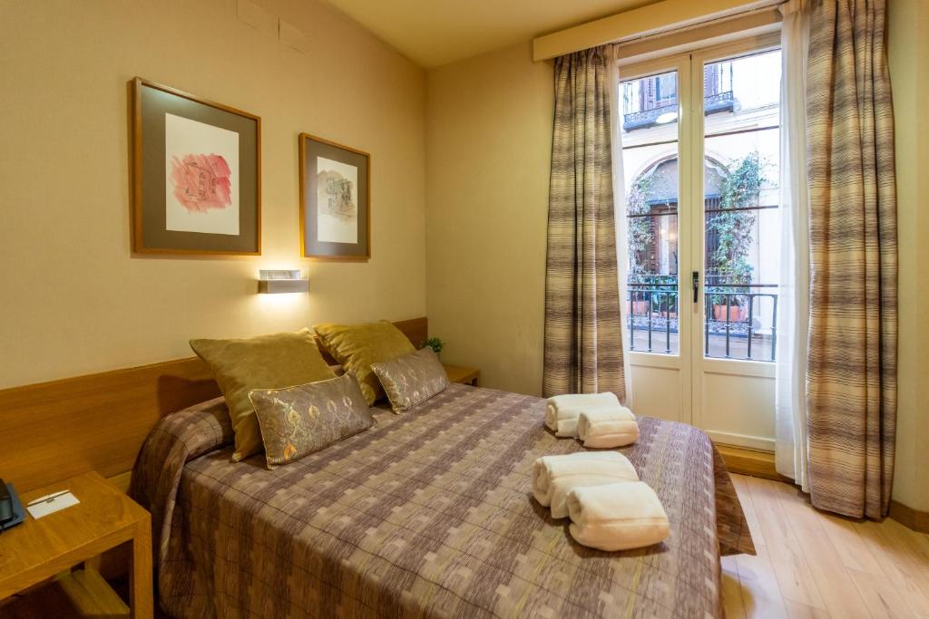 马德里埃尔帕萨赫酒店的一间卧室配有一张带两个枕头的床
