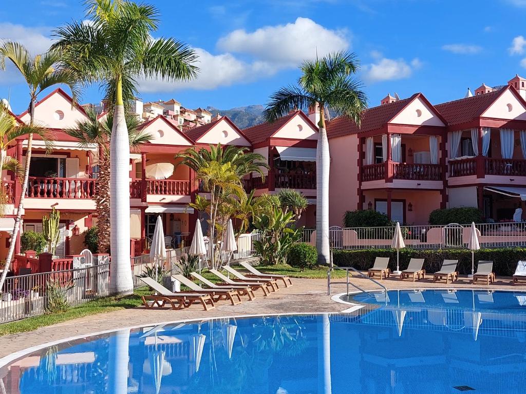 阿德耶Residencia El Duque - 1, VILLA MARIUS的一个带椅子和棕榈树的游泳池的度假酒店
