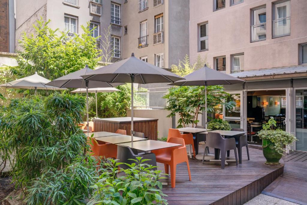 巴黎贝朗布阿城市酒店的一个带桌椅和遮阳伞的户外庭院。