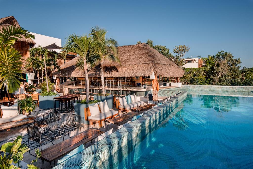 图卢姆Mayan Monkey Tulum的一个带椅子的度假村游泳池和一间酒吧