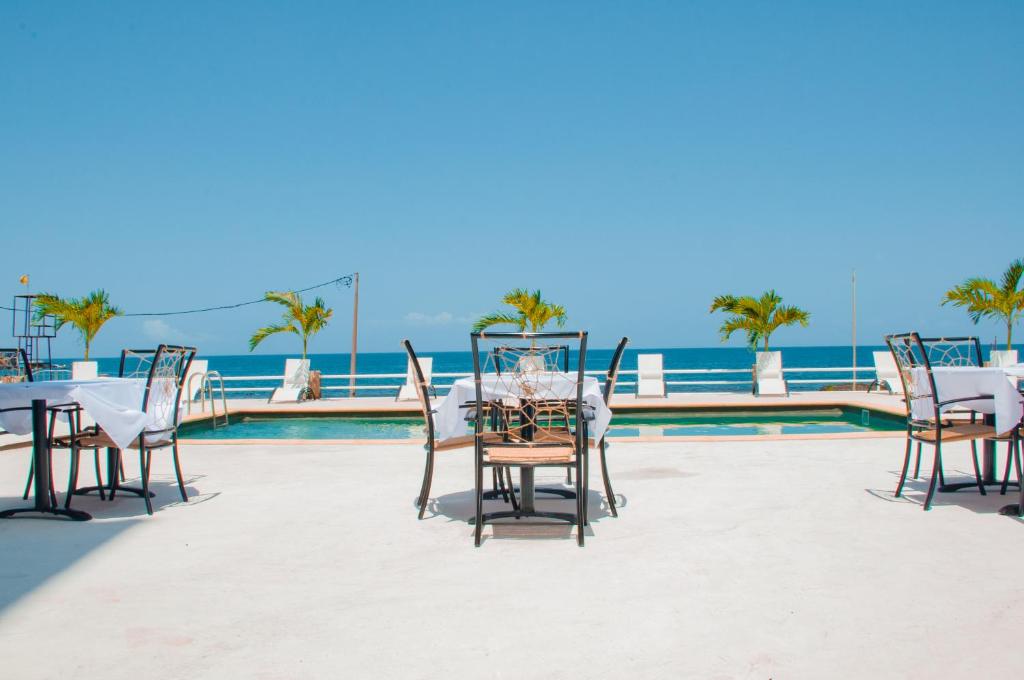 Pedra BadejoFalucho Paradise Beach的游泳池旁的天井上摆放着桌椅