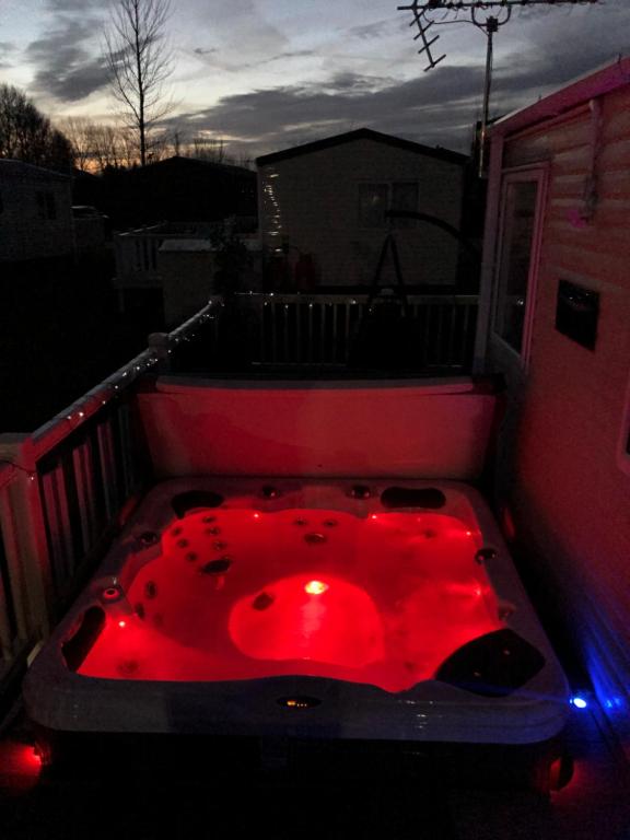 塔特舍尔Static Caravan with hot tub的阳台顶部的红色浴缸