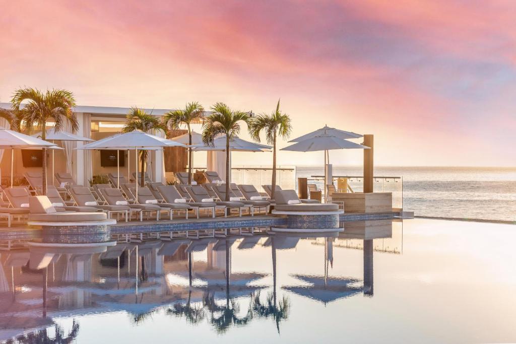 圣何塞德尔卡沃Le Blanc Spa Resort Los Cabos Adults Only All-Inclusive的毗邻大海的带椅子和遮阳伞的游泳池