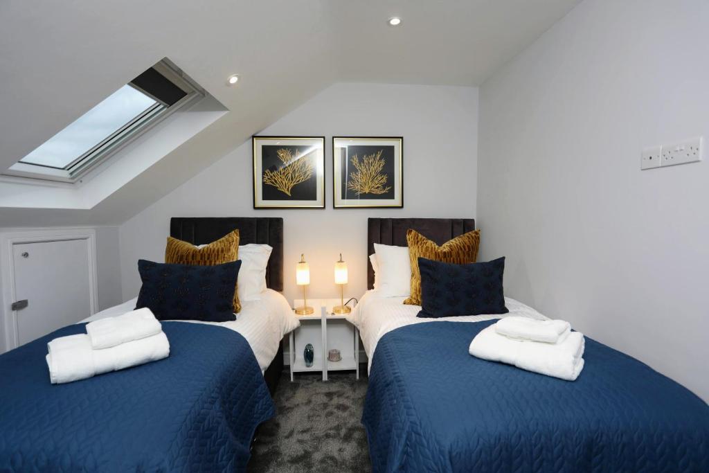 芬奇利Aisiki Apartments at Stanhope Road, North Finchley, a 3 Bedroom and 2 Bathroom Pet-Friendly Duplex Flat, King or Twin beds with FREE WIFI的一间卧室配有两张带蓝白色床单的床