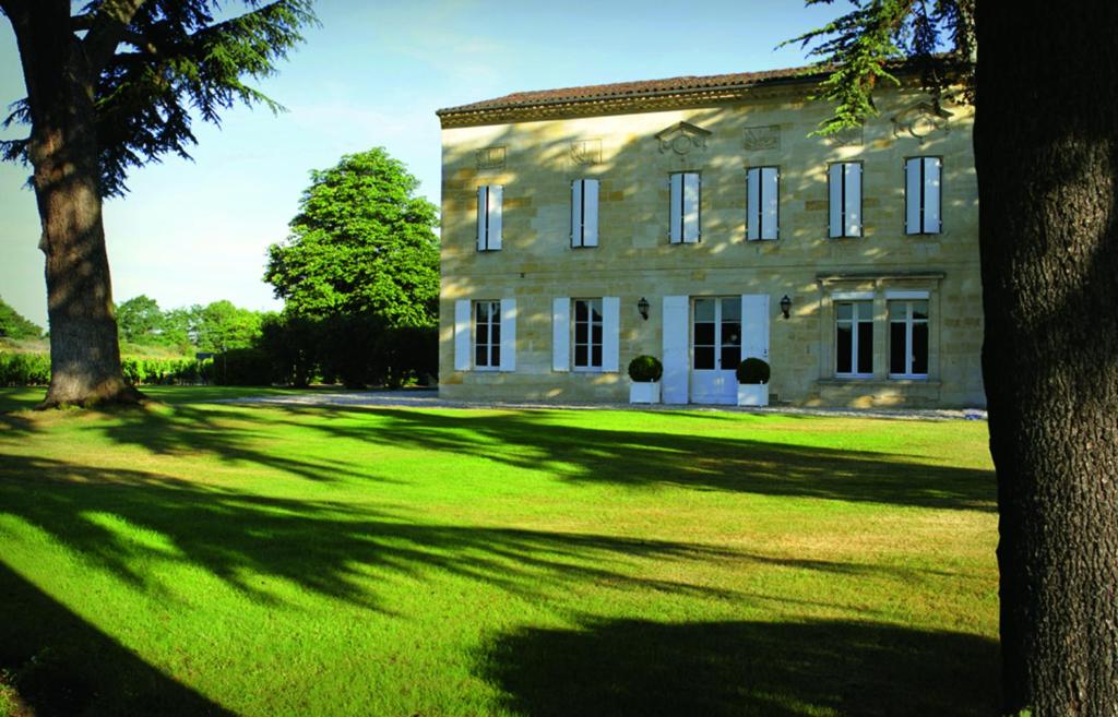 利布尔讷Château Bonalgue - Pomerol的一座大型石头建筑,设有大草地庭院