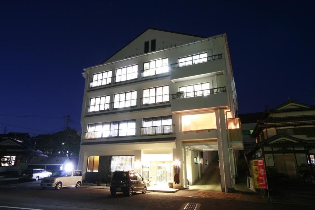 多良鹤莊鹤之御宿日式旅馆的一座高大的白色建筑,晚上有窗户