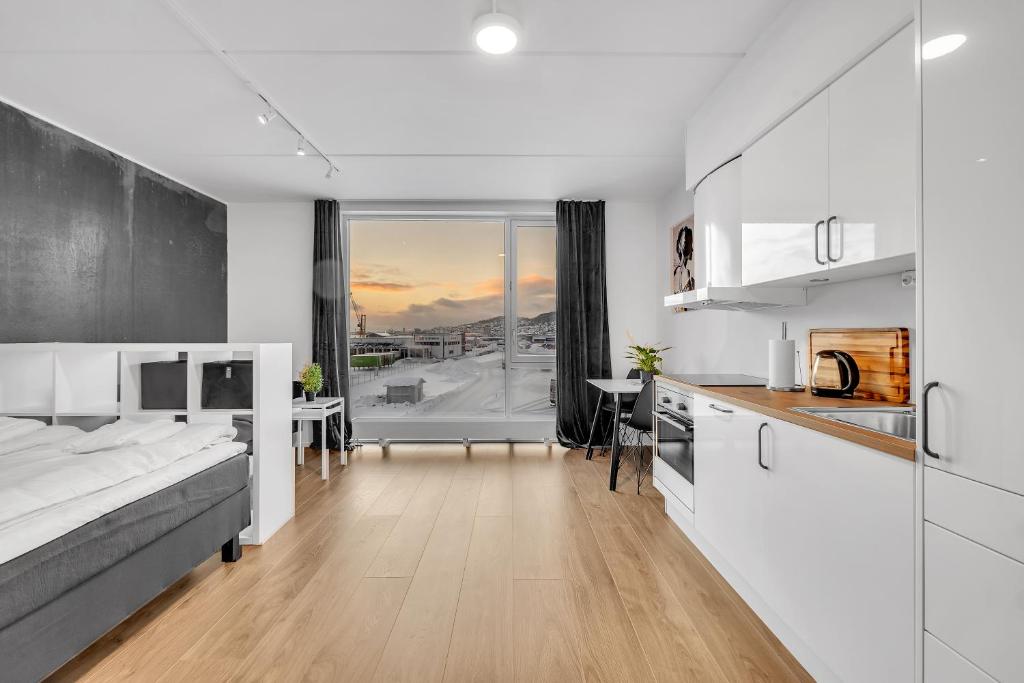 特罗姆瑟TA Stakkevollvegen Studio的厨房以及带白色橱柜和桌子的客厅。