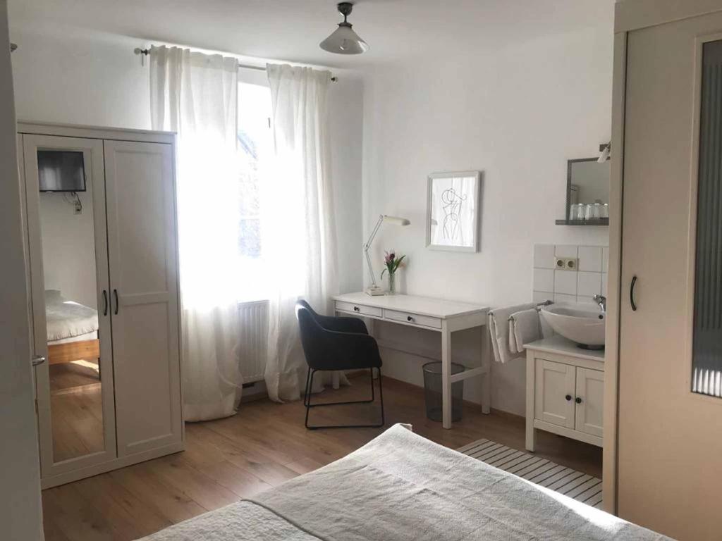多瑙河畔克雷姆斯Gästehaus Lurger的白色的客房设有书桌、水槽和窗户。