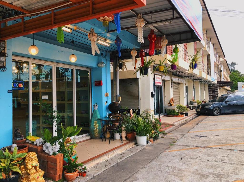罗勇Aekkalukthai Hostel Rayong的商店前方的街道景观,种植了植物