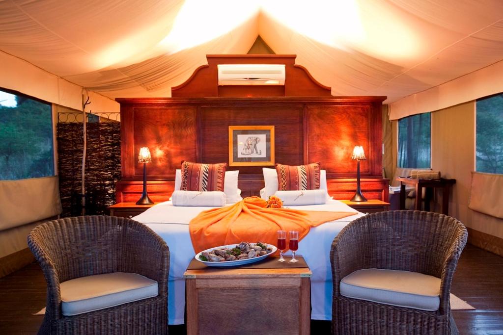 纳姆比提动物保护区The Springbok Lodge的一间卧室配有一张大床和两把椅子