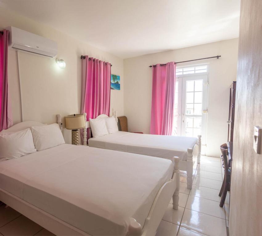 罗索St. James Guesthouse的配有粉红色窗帘的客房内的两张床