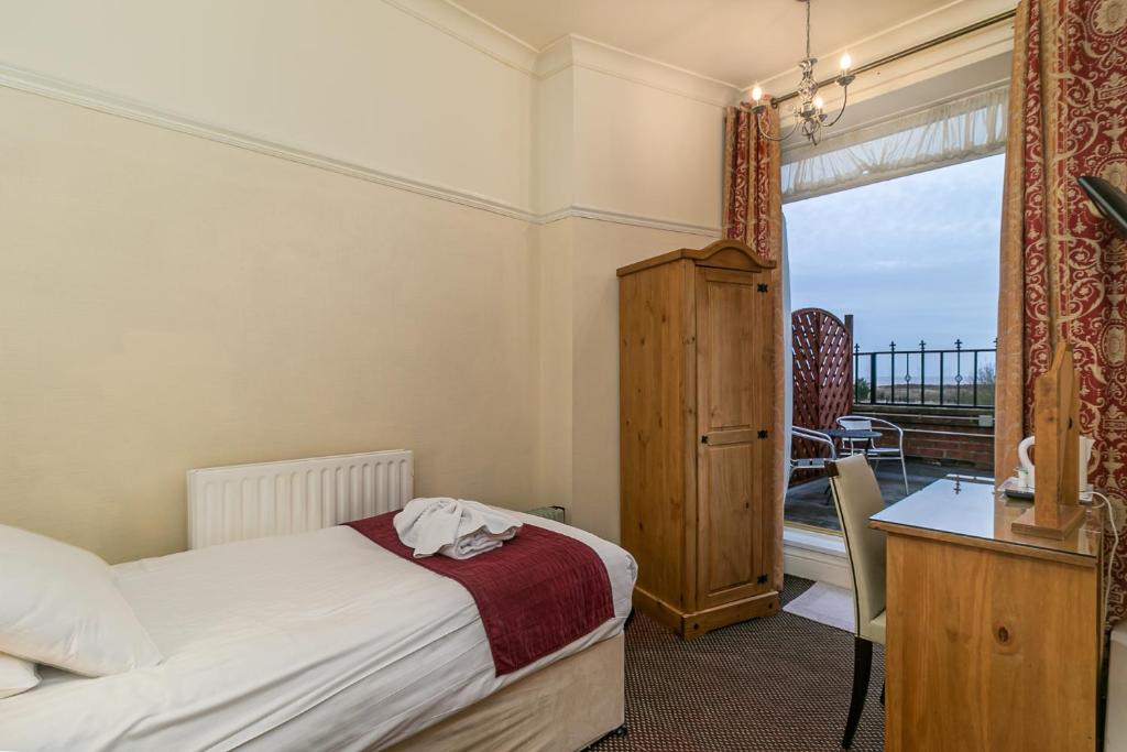 斯凯格内斯皇家酒店的一间卧室配有一张床、一张书桌和一个窗户。
