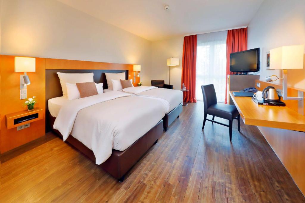 美因河畔法兰克福弗里德博格瓦特贝斯特韦斯特高级IB酒店的一间大卧室,配有一张大床和一张书桌
