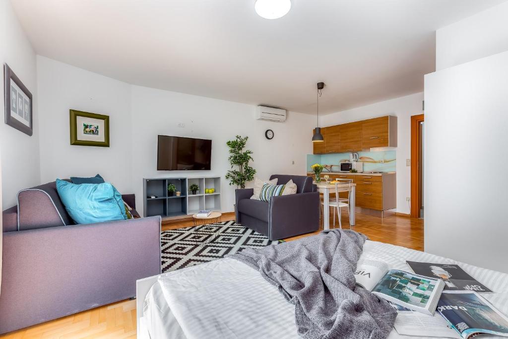 里耶卡Main Street Apartments 2的一间带两张紫色椅子的客厅和一间厨房