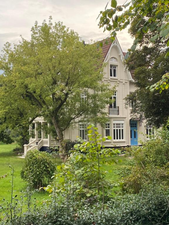 迪尔森-斯托科姆Villa les Bruyères的院子里有树的白色房子