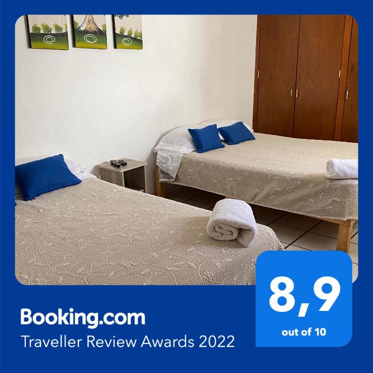瓜达拉哈拉Casa Ejecutivo Zona Iteso Bahía de Acapulco的两张床位,位于酒店客房内,标有旅行评审奖