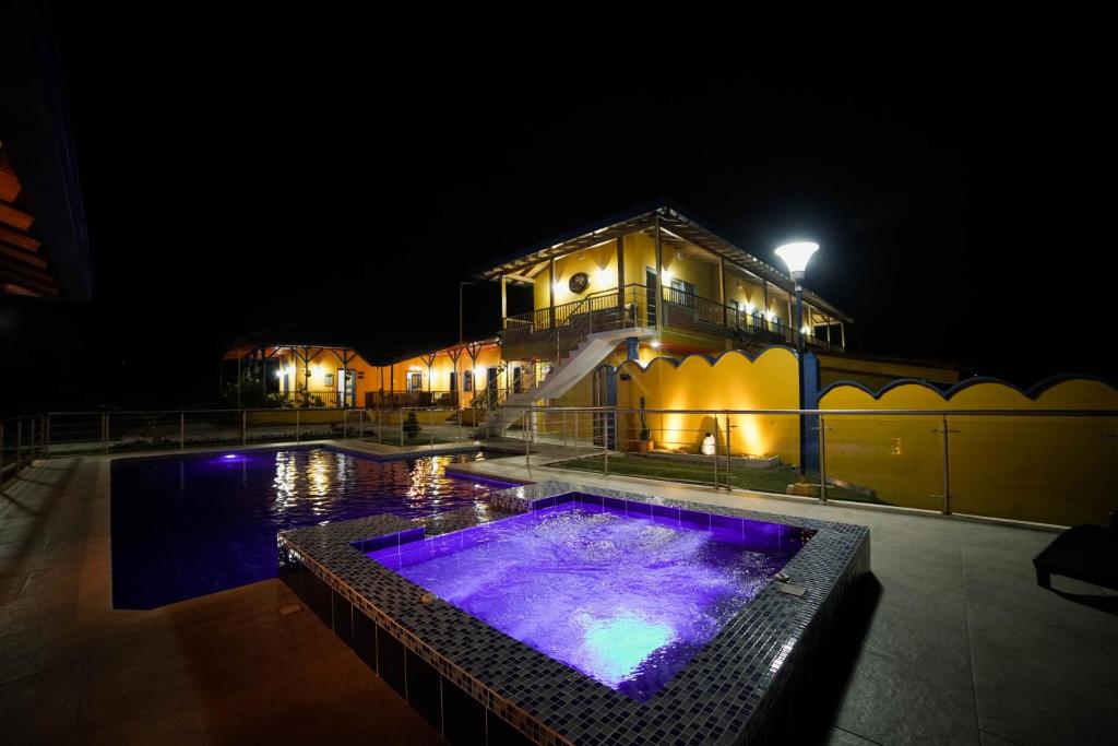 佩雷拉Ecohotel Guaduales Pereira的一座晚上设有游泳池的建筑
