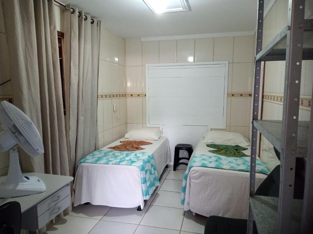 约恩维利Pousada Joinville的小房间设有两张床和一个架子