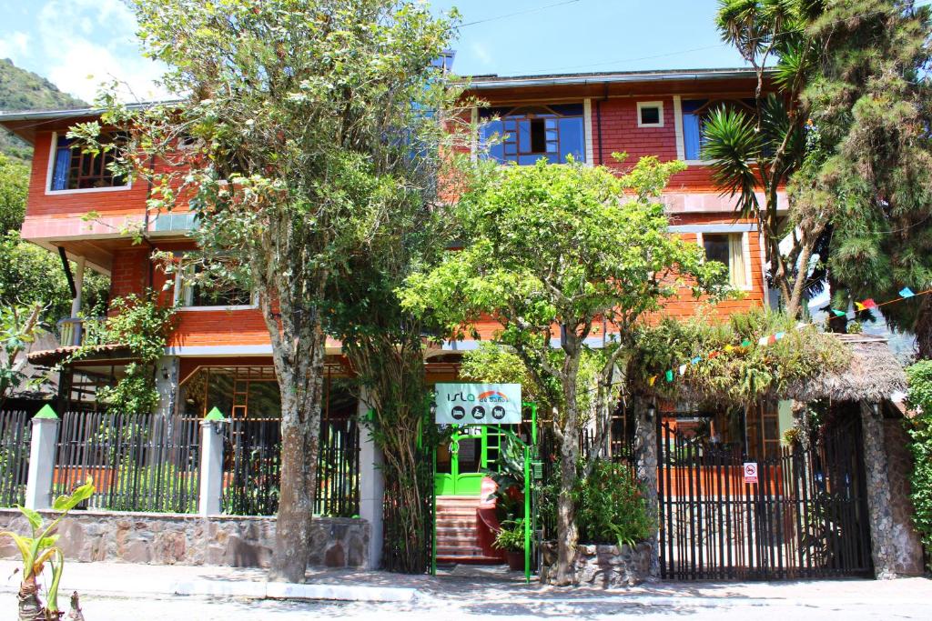 巴尼奥斯Hotel y Spa Isla de Baños的前面有栅栏和树木的房子