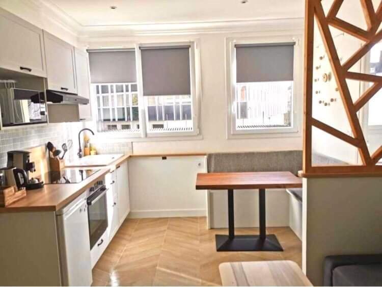 瓦讷Bel appartement rénové, centre de Vannes的厨房配有白色橱柜和木桌