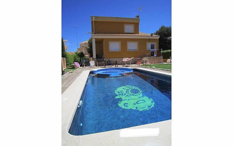 卡塔赫纳Chalet de Lujo en La Manga的一座房子,里面设有一座游泳池,上面有绘画作品