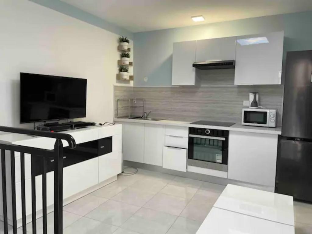 圣但尼WIFI - PARKING - SUPERBE T3 SPACIEUX ET MODERNE!!!!的厨房配有白色橱柜和黑色冰箱。