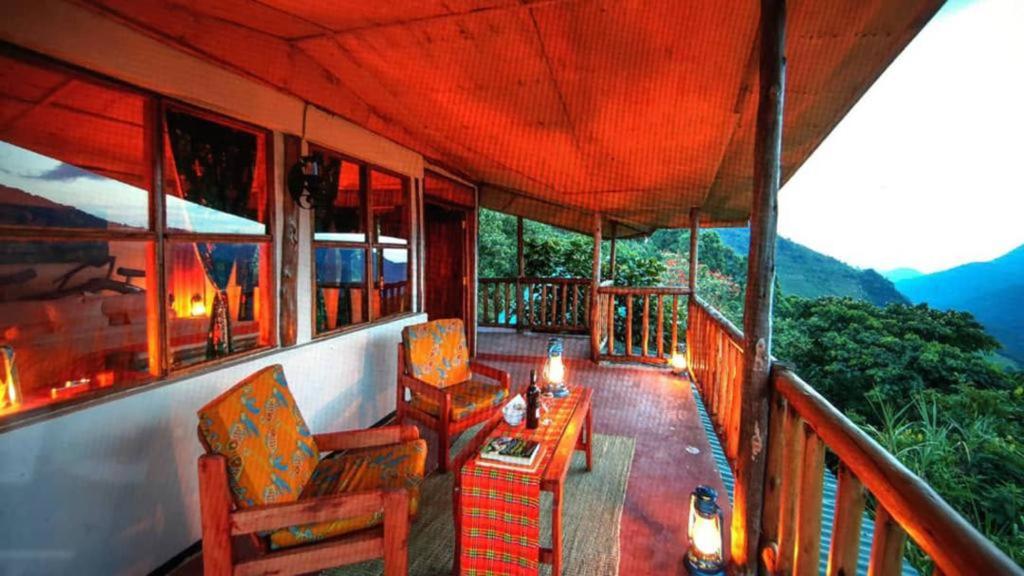 KisoroGorilla Closeup Lodge的阳台,配有椅子和桌子