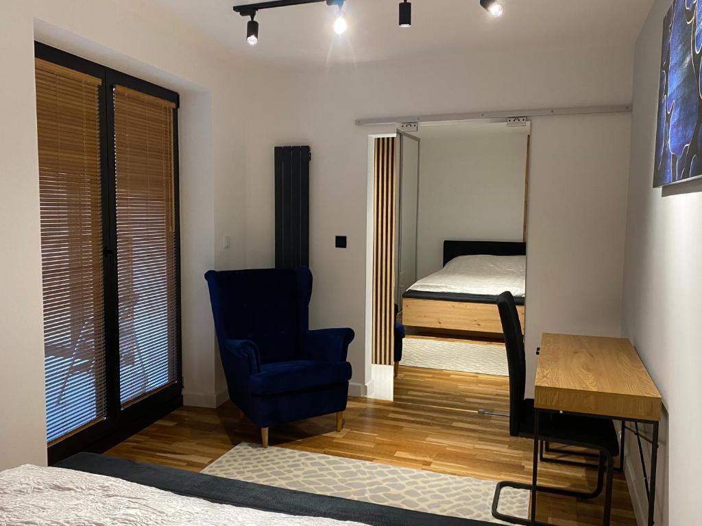 克罗斯诺Kamienica Nova 13的一间卧室配有一张床、一张蓝色椅子和一张书桌