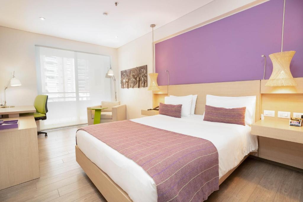 布卡拉曼加Hotel Bari Bucaramanga的酒店客房设有一张大床和紫色的墙壁