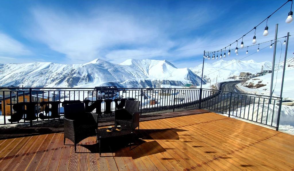 古多里Gudauri Winter House的甲板上配有桌椅,甲板上设有雪覆盖的山脉