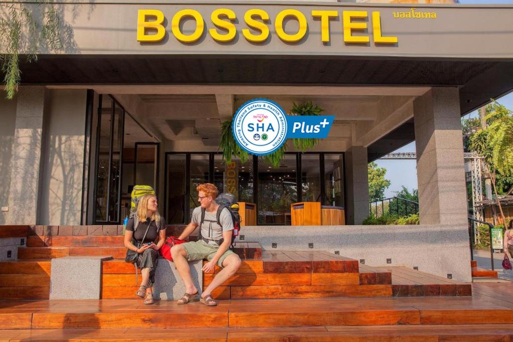 清迈Bossotel Chiang Mai - SHA Plus的两个人坐在生意前的台阶上