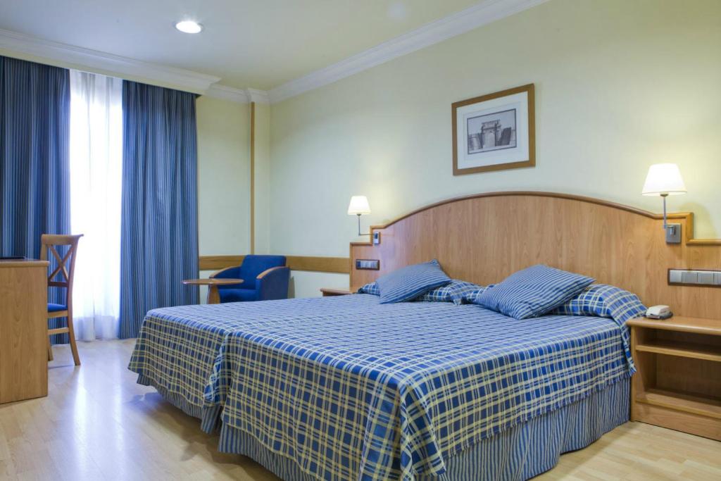 马德里马德里卡斯蒂拉斯二世酒店的一间卧室配有一张带蓝白色毯子的床