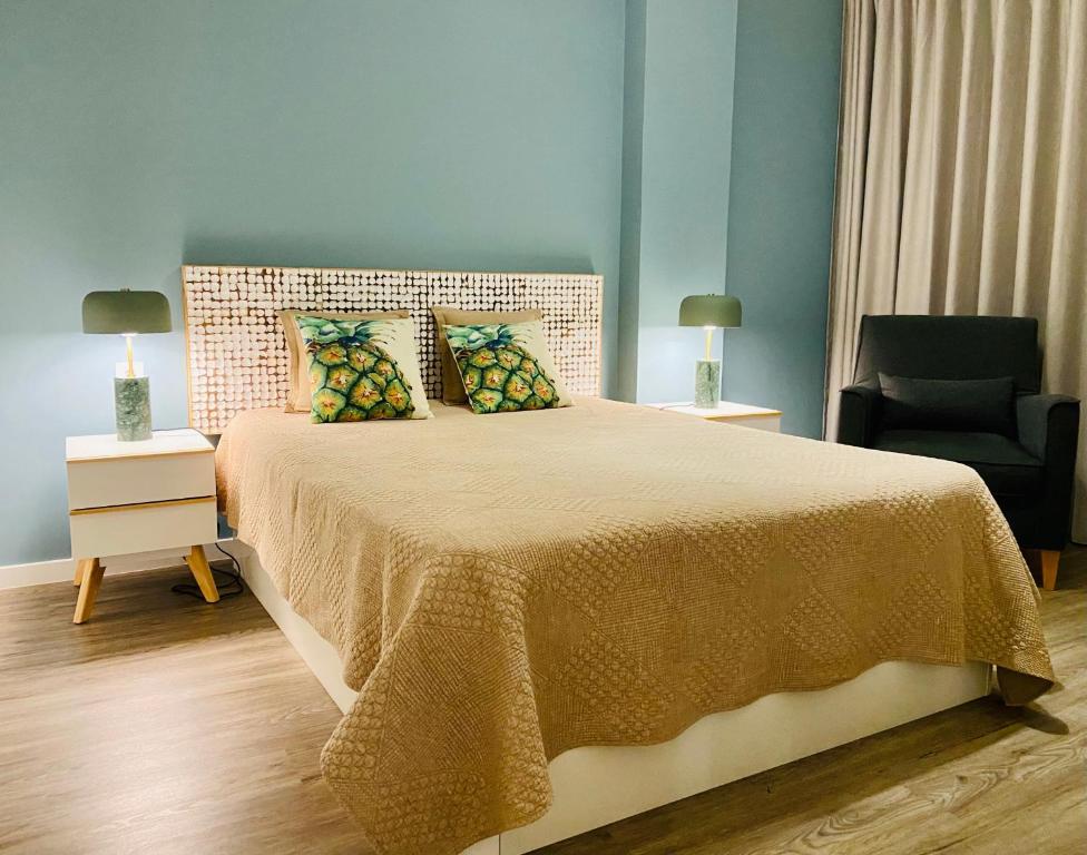 丰沙尔Ocean Cliffs Apartments的一间卧室配有一张大床和一把椅子