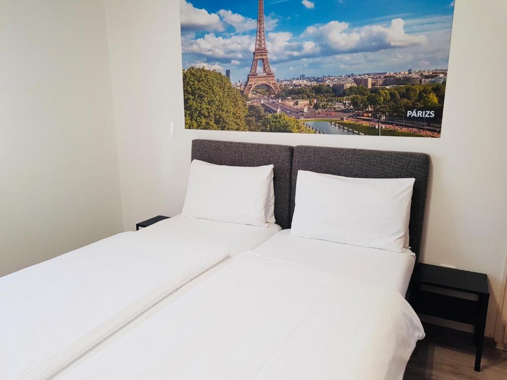 塞格德玛迪亚斯住宿加早餐旅馆的一张位于一间客房内的两张床,享有艾菲尔铁塔的图片。
