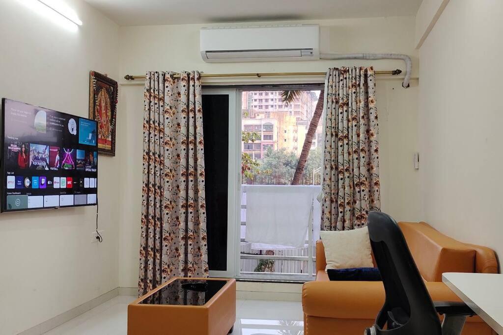 孟买CITY HOMES PARADISE APARTMENT的带沙发和窗户的客厅