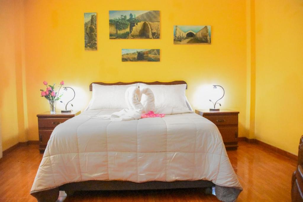伊察Hospedaje Claudia的卧室配有一张白色床、两张桌子和两盏灯。